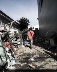 Rear view of man standing by garbage against sky