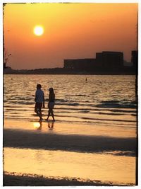 Silhouette of woman in sea at sunset