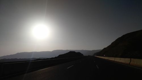 Road by mountains against sky