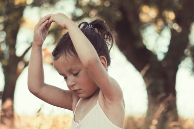 Close-up of girl with hand on tree