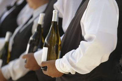 Close-up of hand holding wine bottles