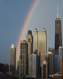 View of rainbow over buildings in city against sky