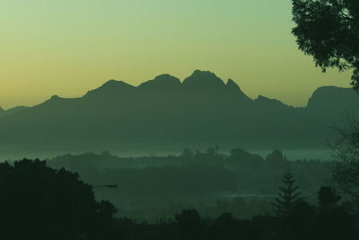 Silhouette trees and mountains against sky during sunset