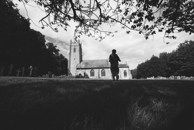 Rear view of man standing on field against sky