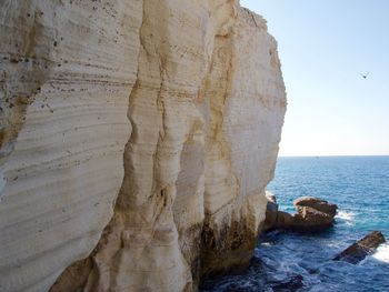 Rock formation in sea against sky