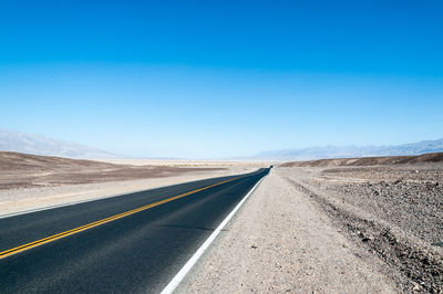 Empty road against clear blue sky
