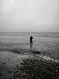 Silhouette men on beach against sky