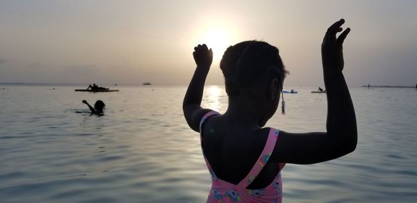 People at beach against sky during sunset