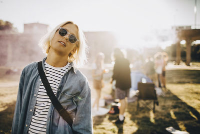 Portrait of young confident man wearing sunglasses standing in music festival