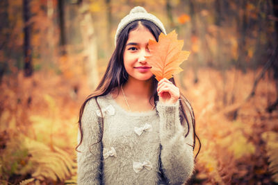 Portrait of beautiful young woman standing in forest during autumn