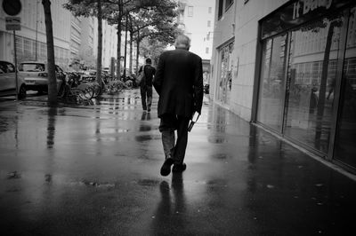 Rear view of man walking on wet street