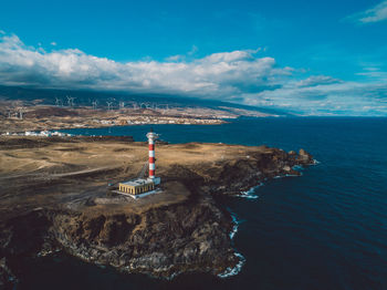 Lighthouse by sea against sky