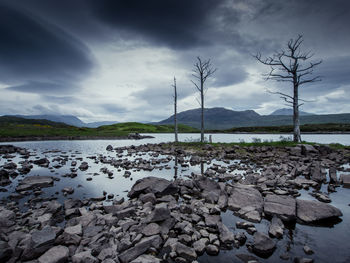 Rocks by river against sky