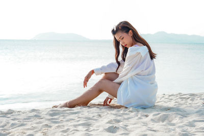 Full length of young woman relaxing on beach