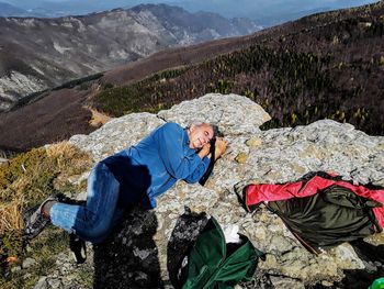 High angle view of man lying on rocky mountain