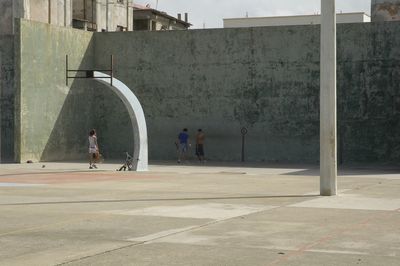 People playing tennis against gray wall