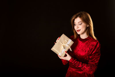 Beautiful young woman standing against black background