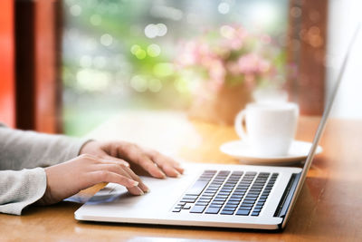 Close-up of woman using laptop on table at home