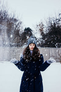 Photo in defocus. young attractive girl throwing snow with her arms. closeup shot.