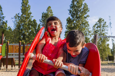 Two kids having fun playing together on a playground in a park.