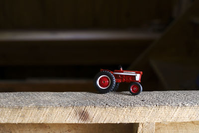 A red toy tractor on a ledge in a barn