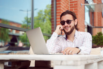 Young woman using mobile phone while sitting on table