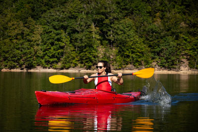 Man holding boat in lake against trees