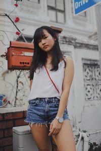 Portrait of smiling young woman standing against building in city