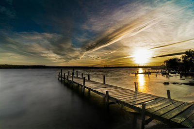 Pier over lake against sky during sunset