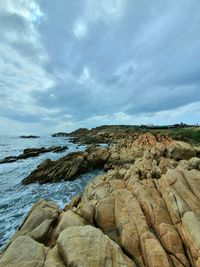 Rock formations on shore against sky