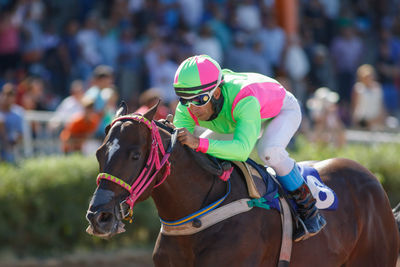 Full length of jockey riding horse