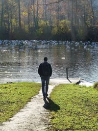 Rear view of man standing by lake