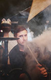 Portrait of young man smoking hookah