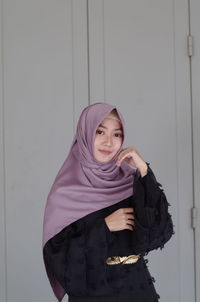 Portrait of beautiful young woman standing against wall