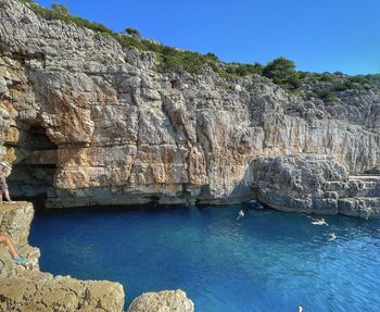 Rock formations by sea against clear blue sky