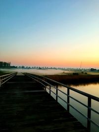 Bridge over river against clear sky during sunset