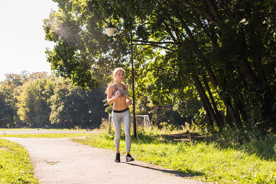 Young woman standing by tree against plants