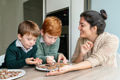 Mother and sons preparing food on table at home