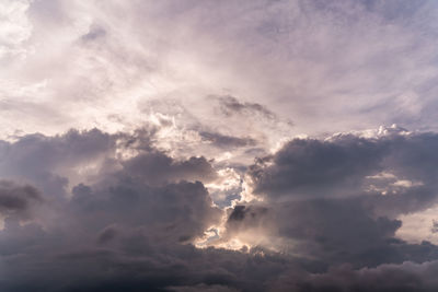 Low angle view of sunlight streaming through clouds