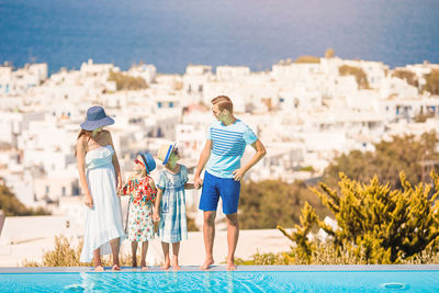 Rear view of people at swimming pool against sea