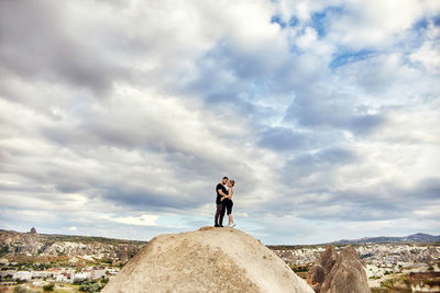 Man standing on rock against sky