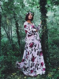 Portrait of woman standing by tree in forest