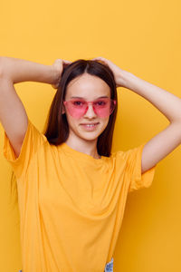 Portrait of young woman against yellow background