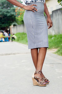 Crossed legs of a young woman on high shoes posing in the street.