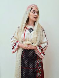 Portrait of young woman standing against white background