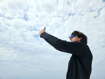 Low angle view of young man standing against sky