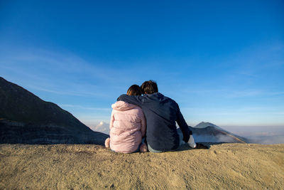 Rear view of couple on mountain against sky