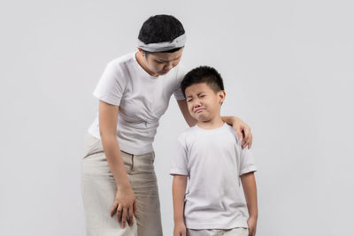 Father and son standing against white background