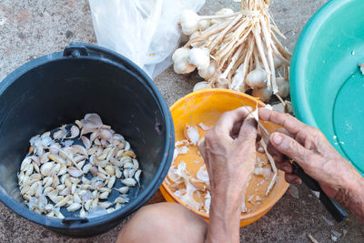 Midsection of man peeling garlic by containers