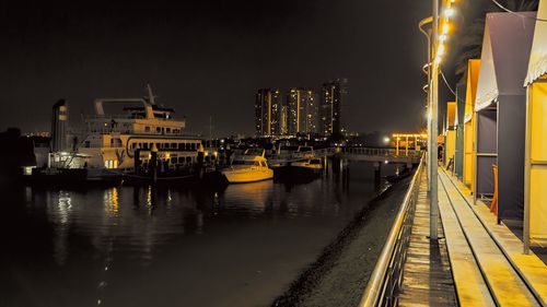 Illuminated harbor by river against sky at night